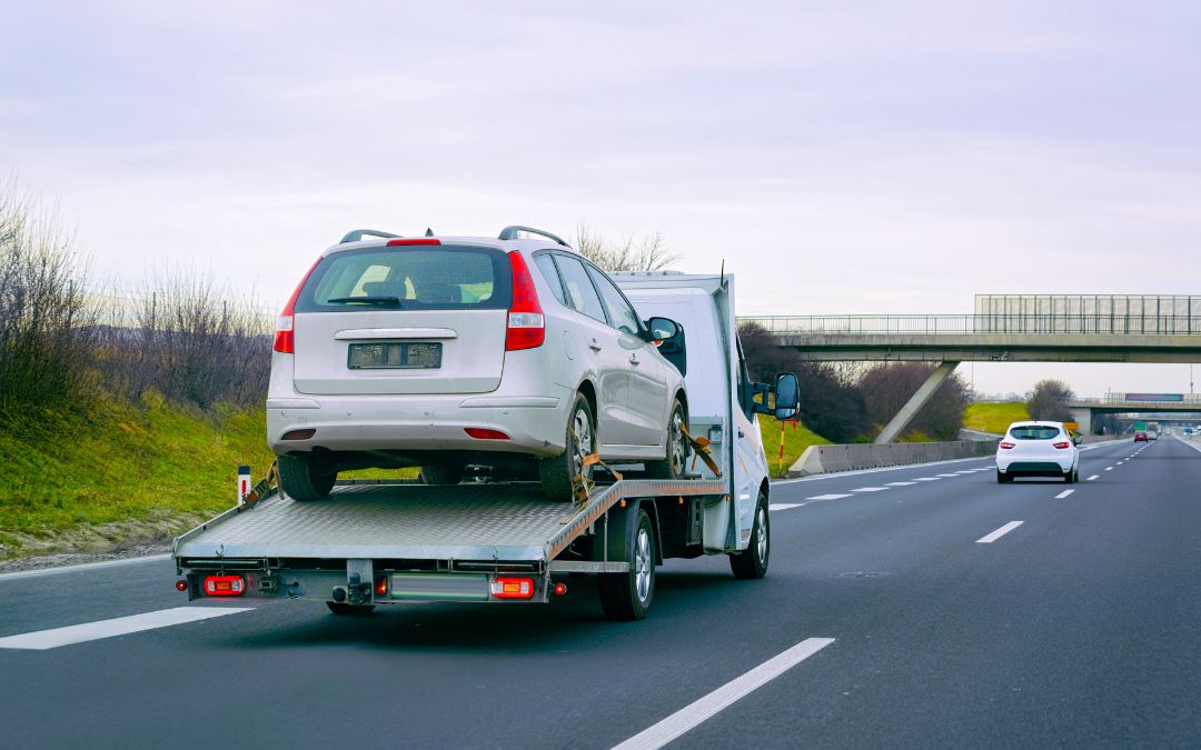 flatbed truck towing car on highway